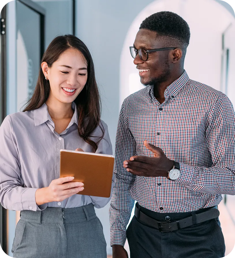 image of an asian female & a black male in busienss casual smiling & talking while they look at a notepad