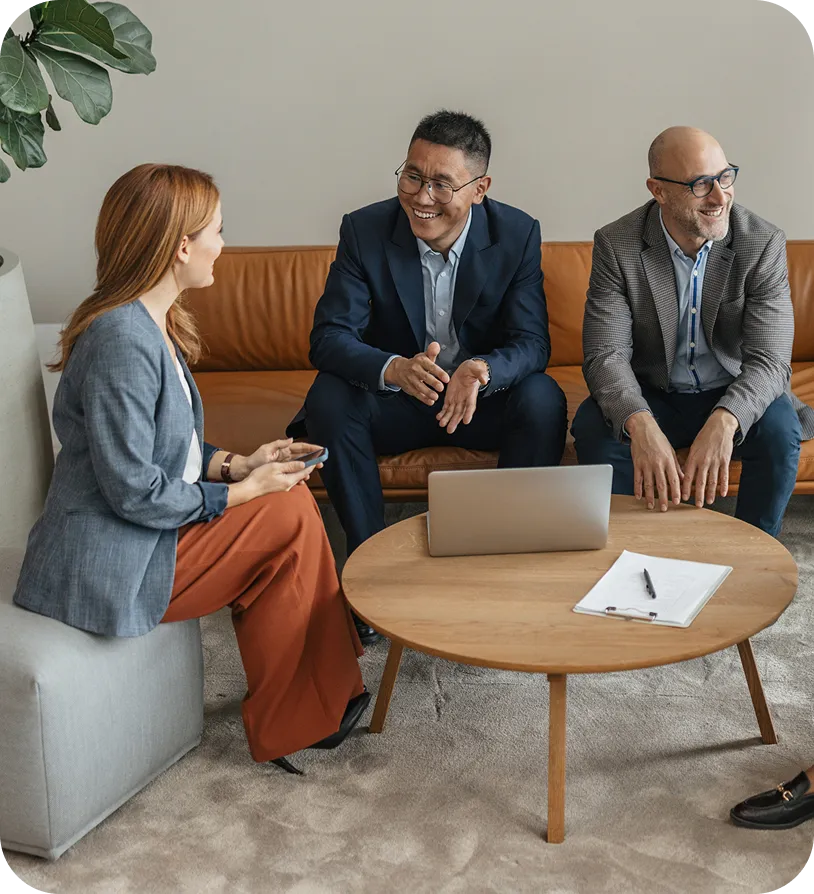 image of people sitting on lounge furniture in front of a coffee table, smiling & talking